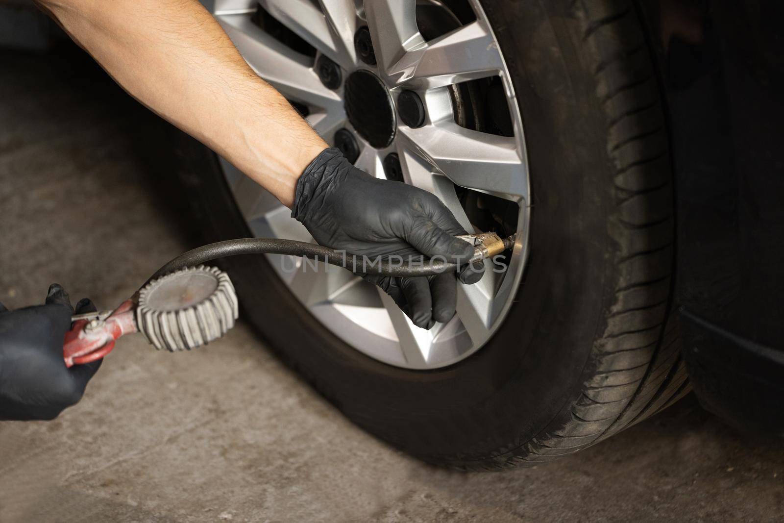 Car tire pressure check using air pressure guage. Mechanic inflating a car tire. Gas pumping of a car wheel. Car tire inflation by uflypro