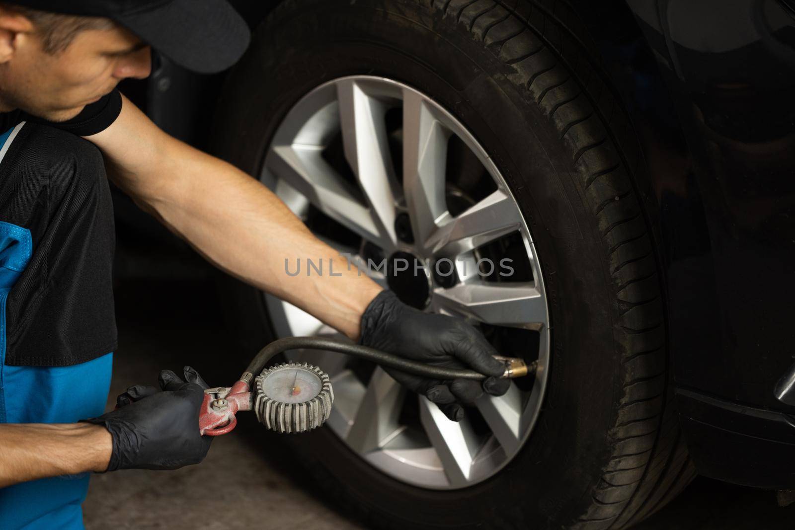 Gas pumping of a car wheel. Car tire inflation. Car tire pressure check using air pressure guage. Mechanic inflating a car tire.