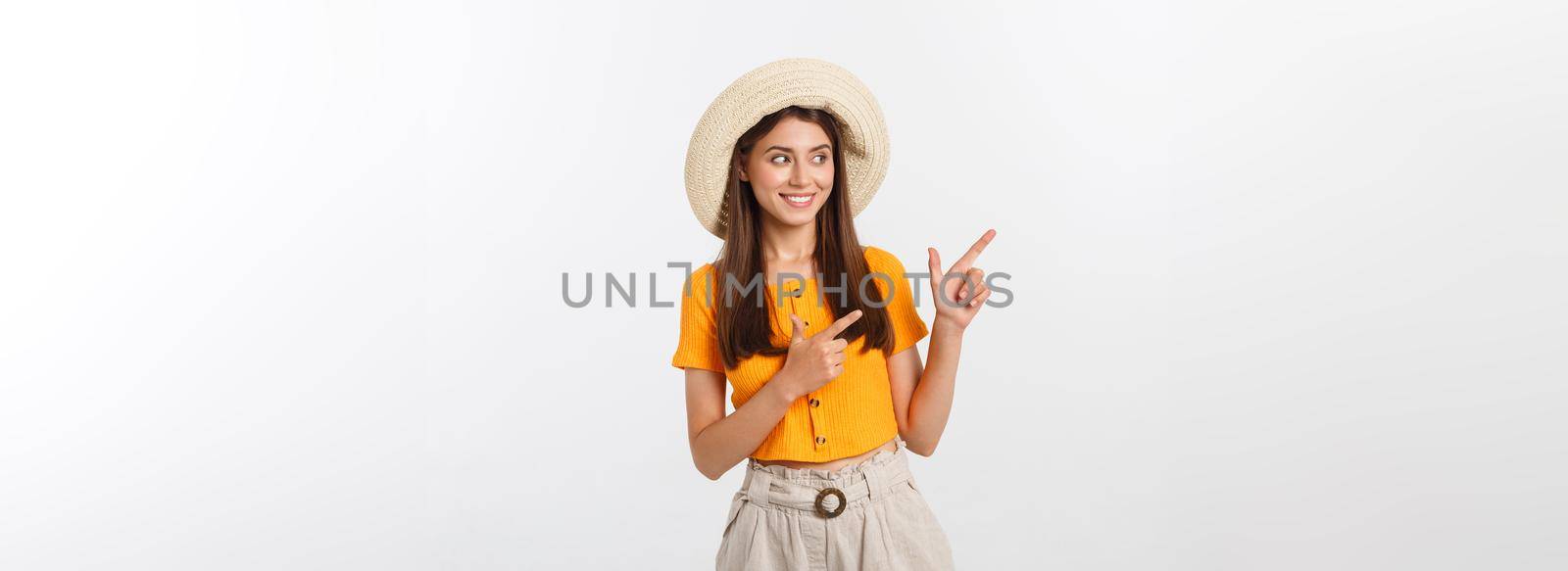 Teenager girl on summer vacation surprised and pointing finger on copy space over isolated white background