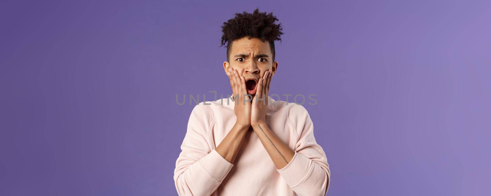 Oh gosh thats terrible. Portrait of shocked, speechless and worried young man express compassion finding out friend got in trouble, gasping open mouth and stare startled camera, touch face in shook by Benzoix