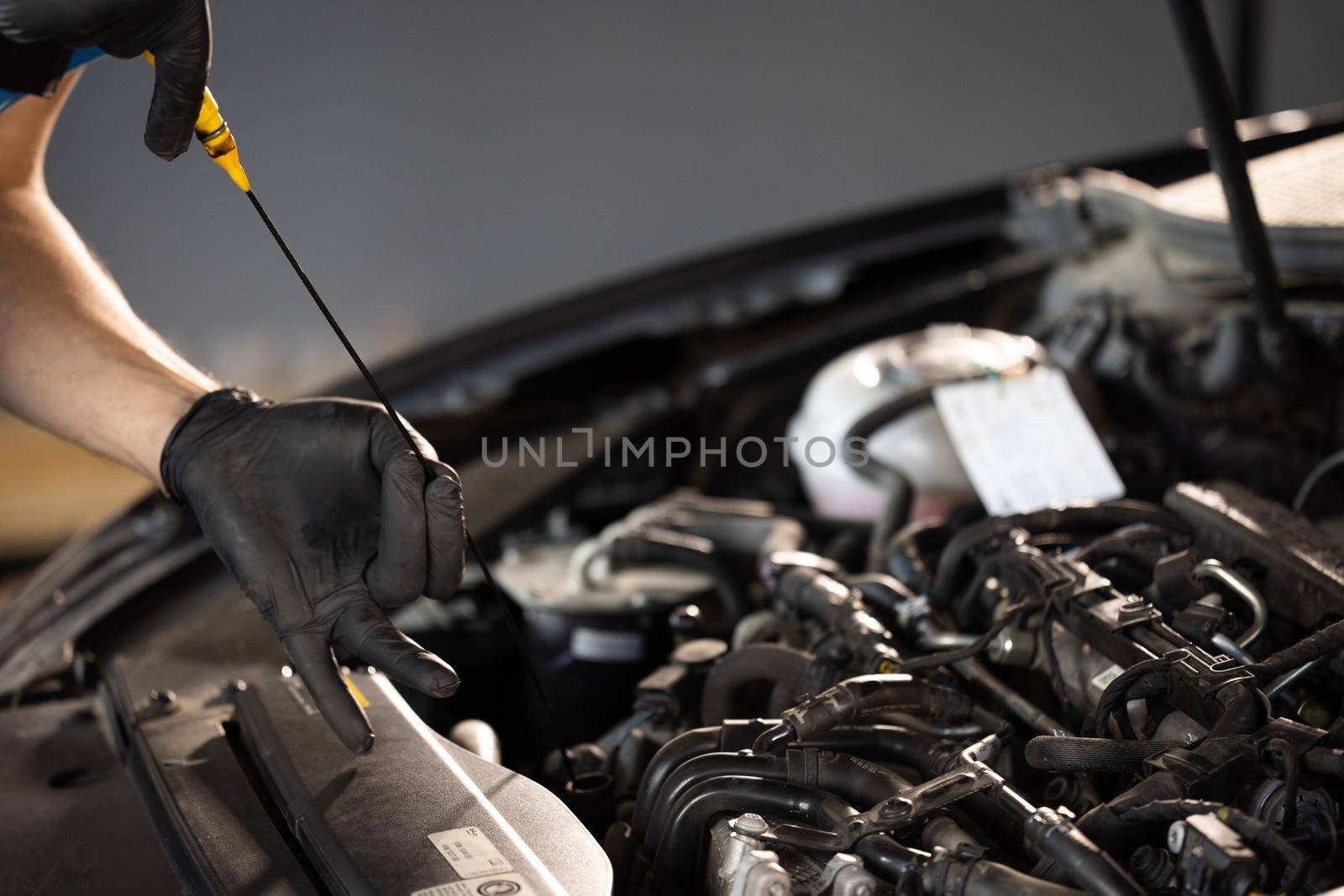 The car mechanic is checking the engine oil level. Overheating of car engine. Motor with open hood. Checking the engine oil car maintenance Remove the dipstick to view the engine oil level by uflypro