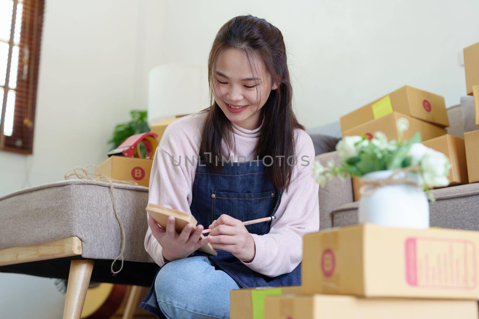 Portrait of Starting small businesses, Asian woman check online orders Selling products working with boxs freelance work at home office, sme business concepts