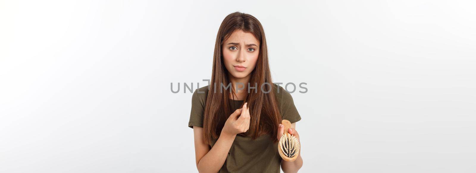 Closeup unhappy frustrated young woman surprised she is losing hair, noticed split ends receding hairline. Gray background by Benzoix