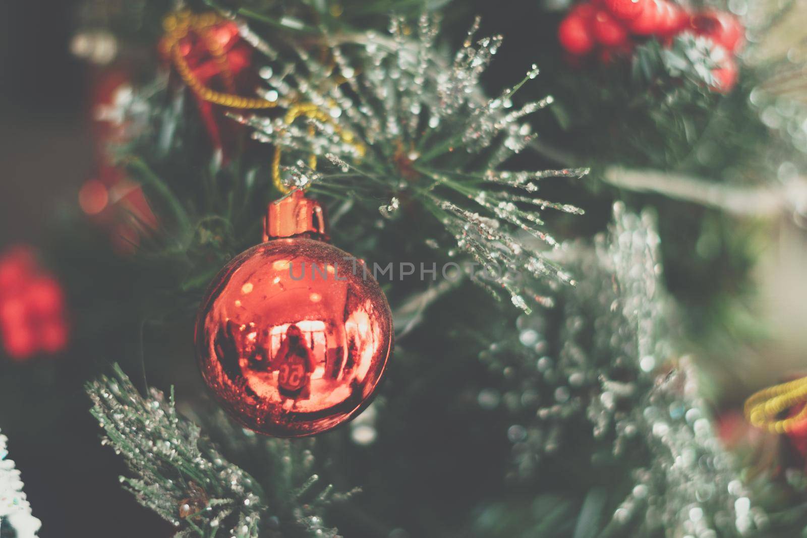 Christmas tree artificial decorative plastic green shiny sequins sprinkles, LED garland light, red ball toy reflection. Winter holiday leisure. Vintage wash matte effect tone.