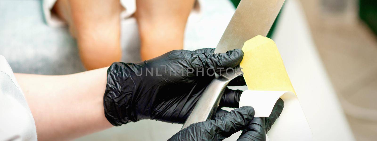 The pedicure master putting on new sandpaper on the metal handle before the procedure of cleaning the foot and heel in a nail salon