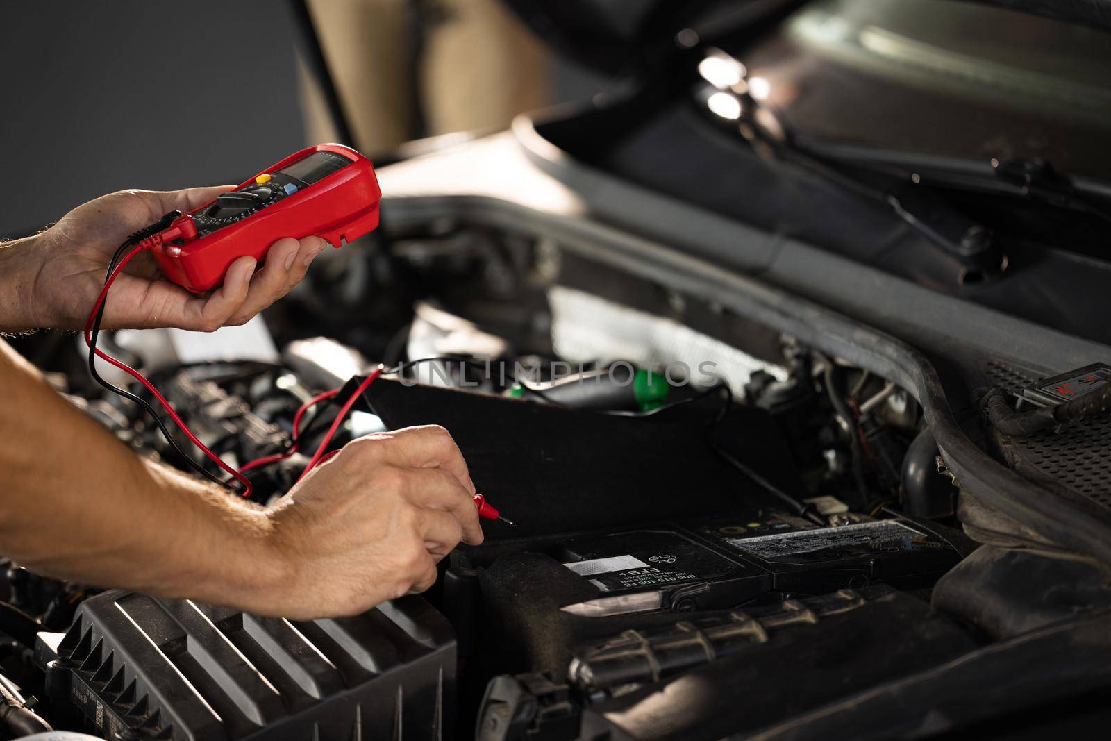 Man using multimeter to measure the voltage of the batteries. Mechanic doing car inspection, he is testing car battery with tester. Check battery voltage with electric multimeter by uflypro