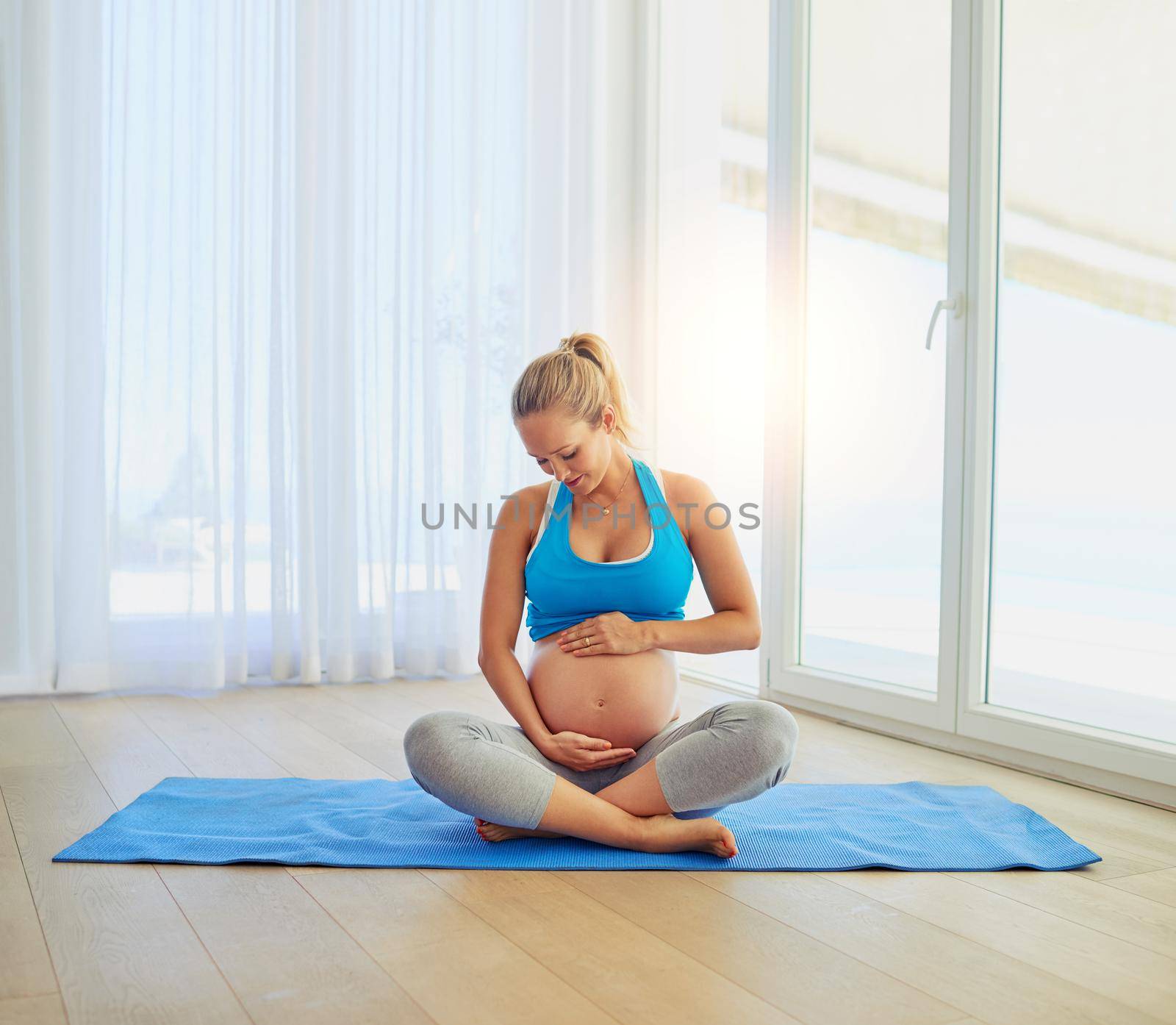 Baby loves it when she works out. a pregnant woman working out on an exercise mat at home