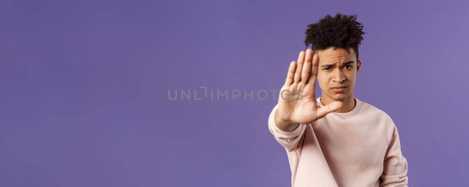 Man you should stop. Close-up portrait of young serious-looking male friend trying to warn person of doing something bad, raise hand to prohibit, forbid no trespassing, purple background.