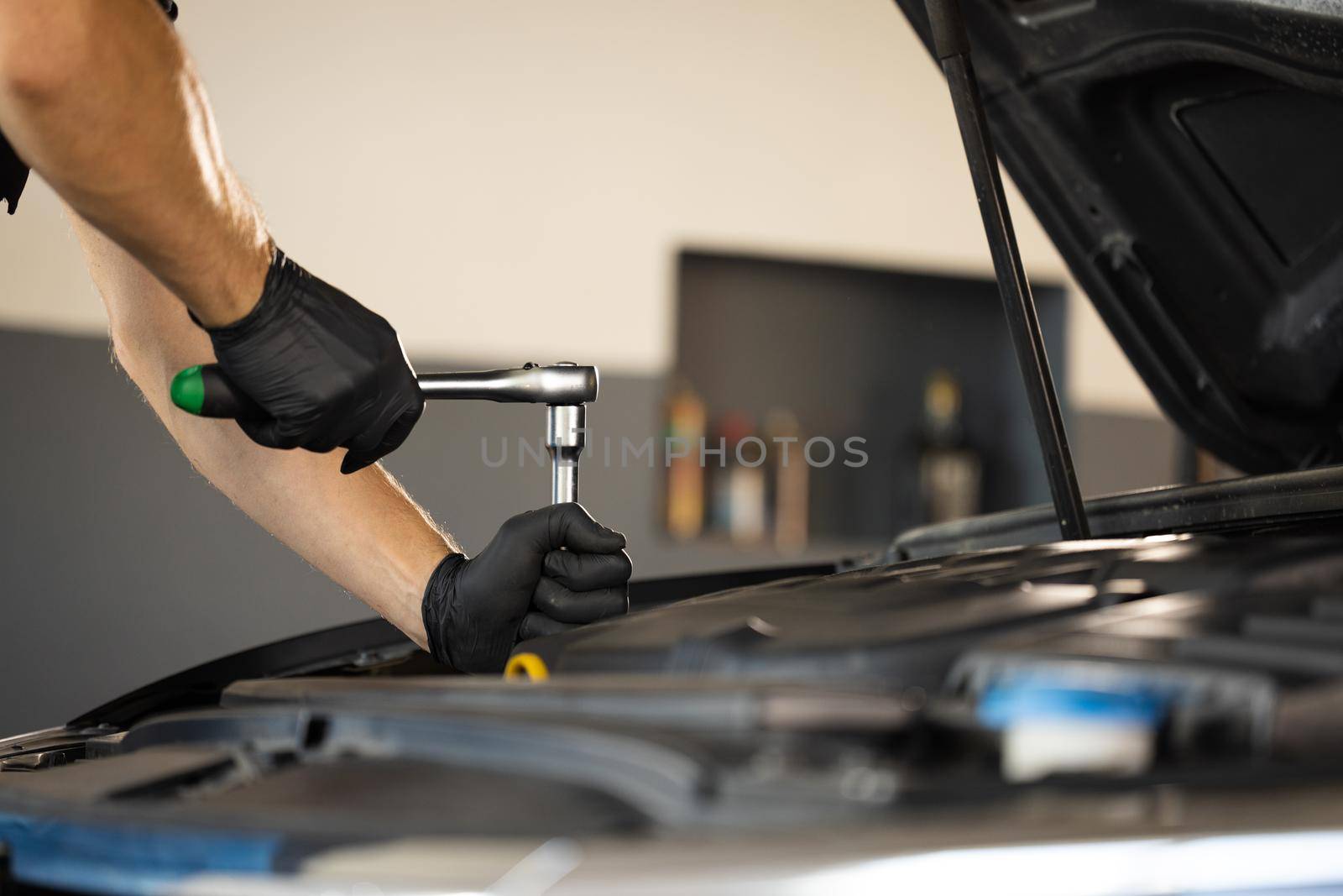 Close Up Footage of a Male Mechanic Using a Ratchet Working on Car in a Car Service. Modern Car Workshop. Auto Service.
