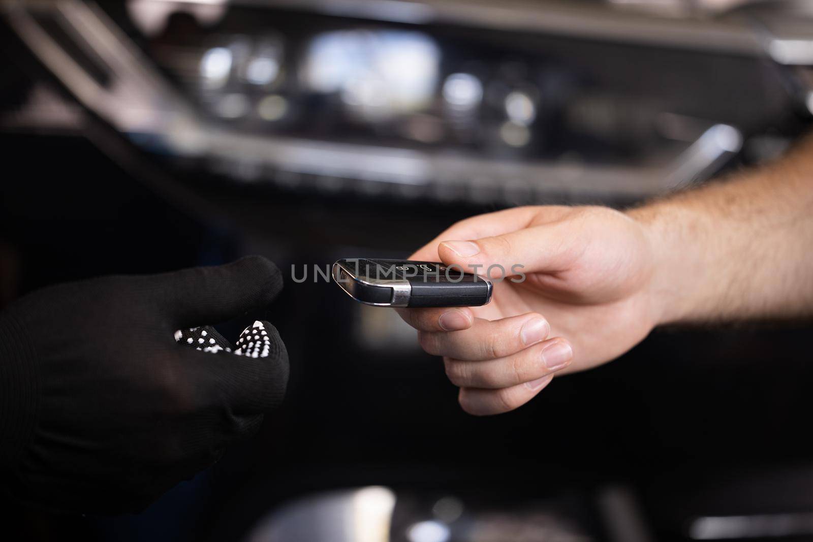 Man owner of the auto gives the keys to the car repairman. Close up shot of hands of male client giving car key to mechanic in auto repair shop. Car repair. Vehicle breaks down.