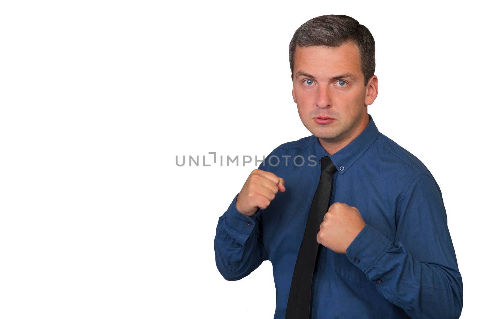 Man in blue shirt and tie with angry facial expression, hands clenched into fists and two hands raised up, isolated on white background.