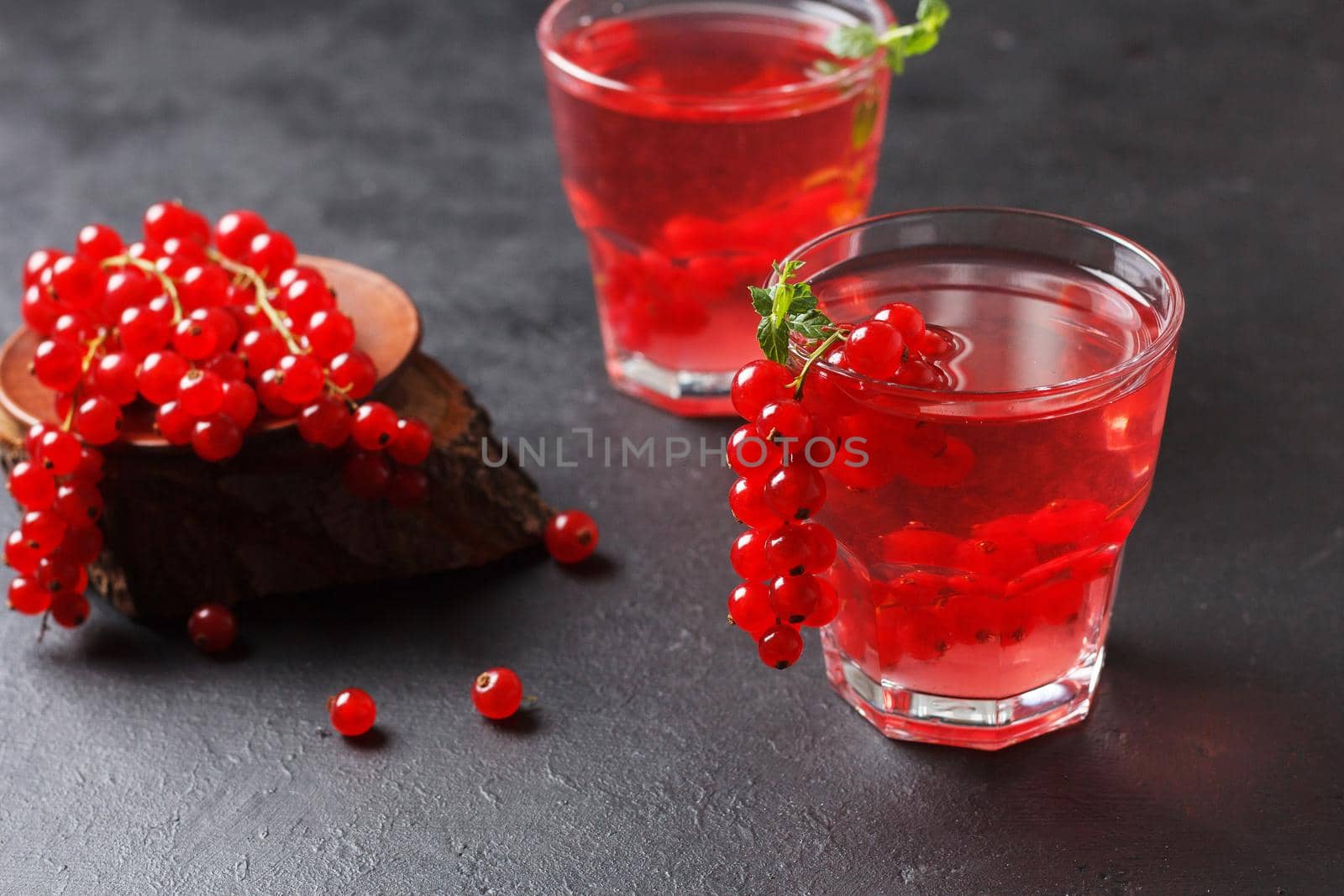 Redcurrant vitamin drink in a glass on a black background with currant berries. healthy eating by lara29