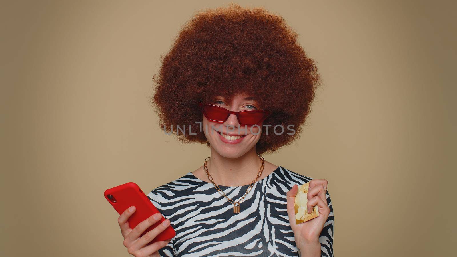Happy young woman use smartphone, plastic credit bank card, browsing say wow yes, found out great big win, success lotter, good news, purchases online shopping. Adult girl on beige studio background
