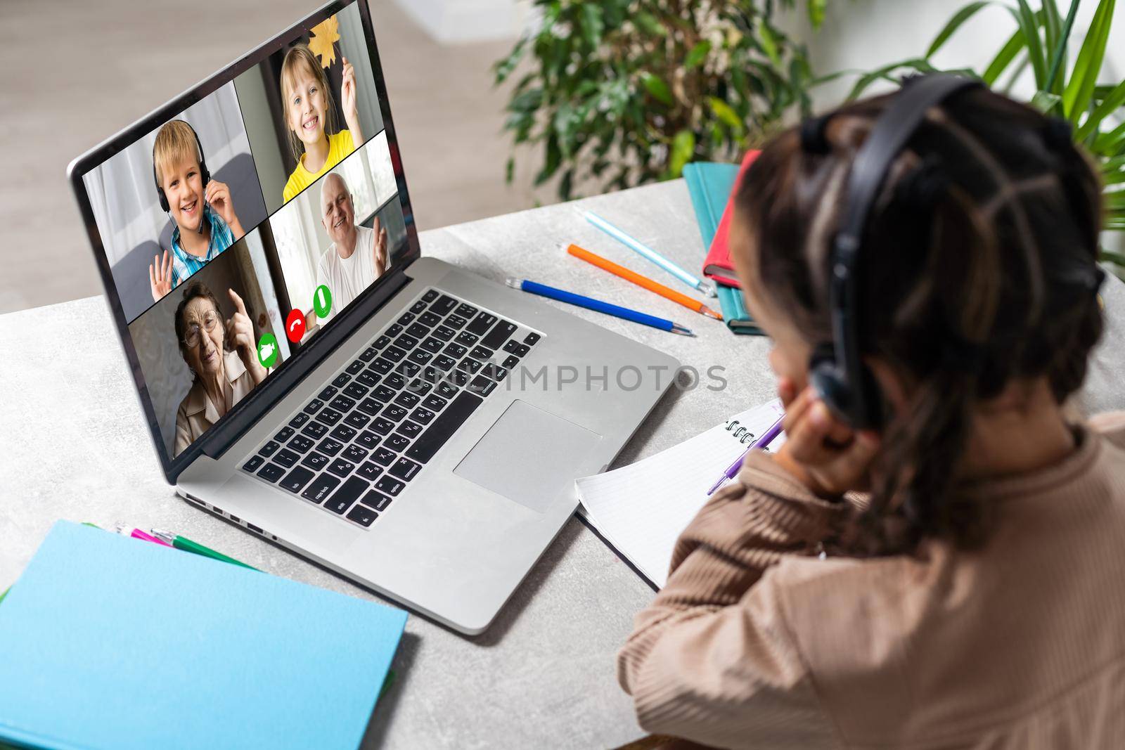 E-Learning. Shocked Little Schoolgirl Looking At Laptop Wearing Headphones Looking At Computer Web Camera In Shock Making Video Call And Learning Online At Home. Shocking News Concept. by Andelov13