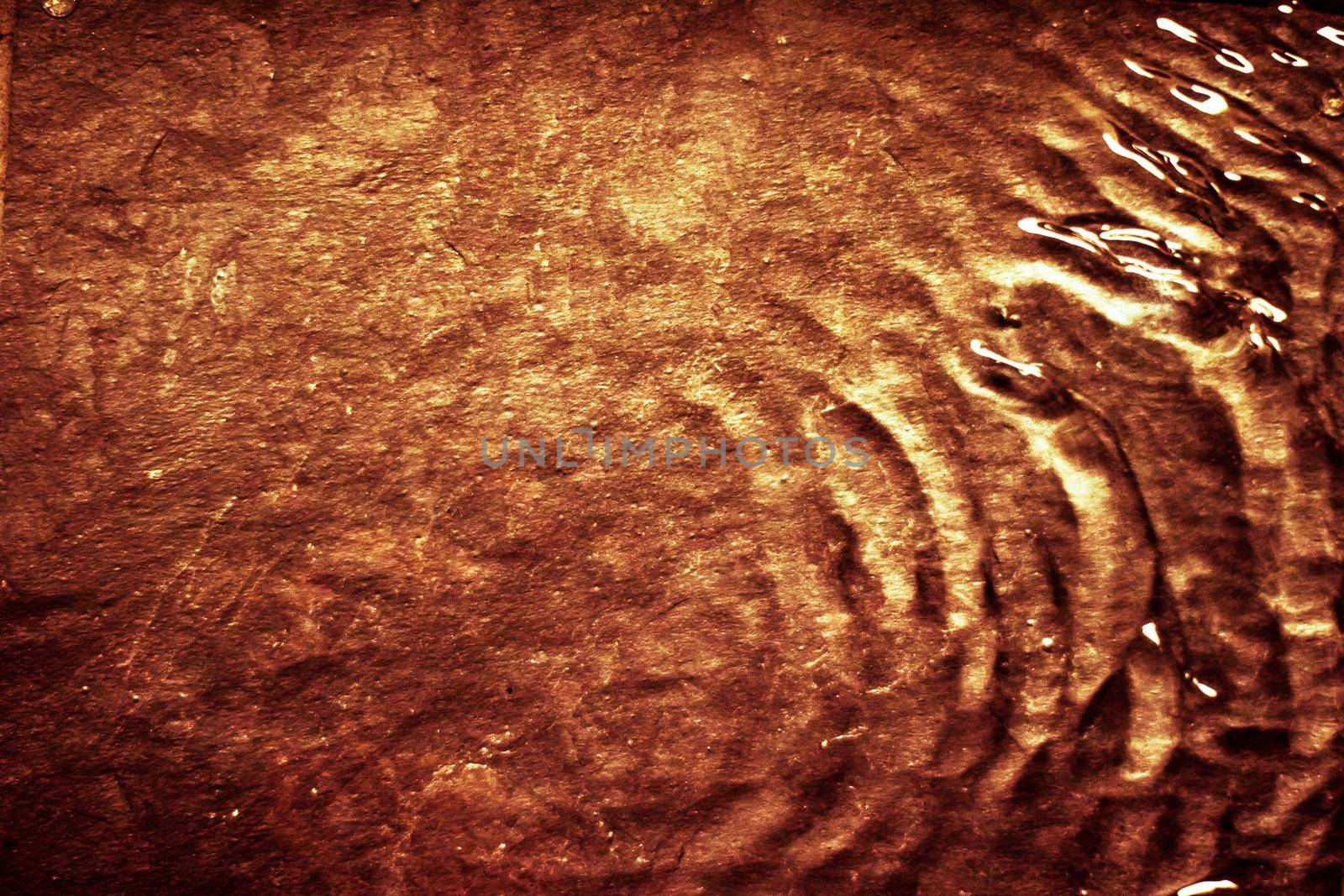Flowing liquid on gold surface - luxury background and abstract design concept. Golden source