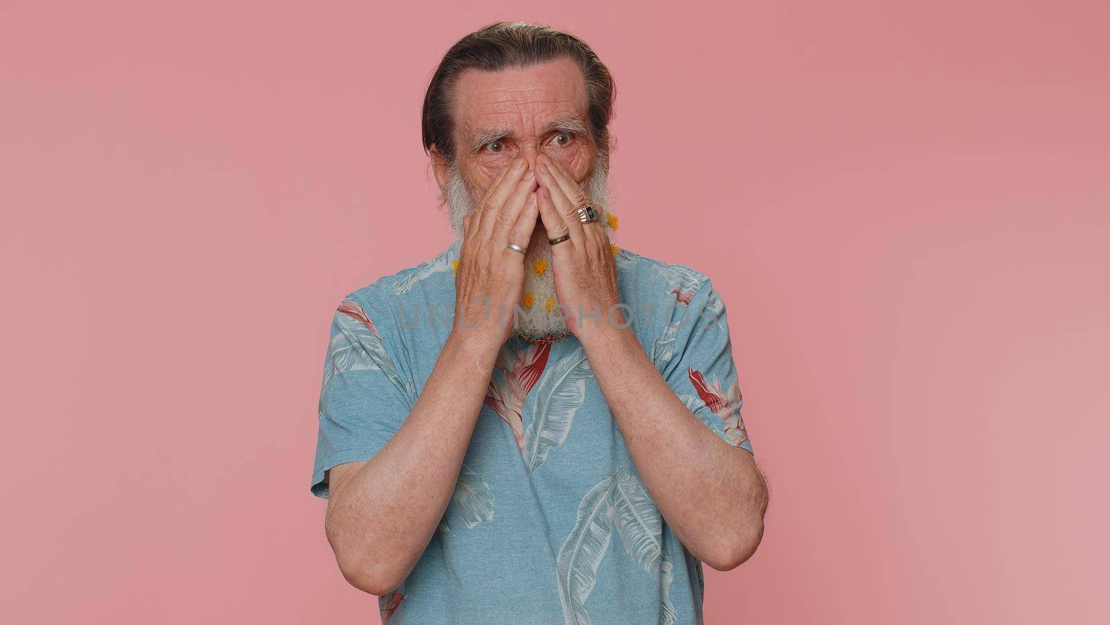 Stressed depressed mature flowered beard mature man expresses his fear and waves his hands away from danger, waving no. Scared fearful senior grandfather isolated alone on pink studio wall background