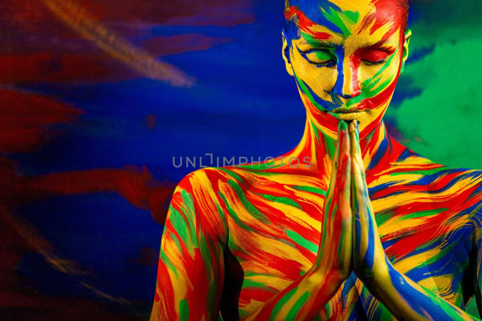Color art face and body painting for inspiration. Woman in namaste yoga asana. Closeup portrait of the bright beautiful girl with colorful make-up and bodyart. Woman with closed eyes. by MikeOrlov