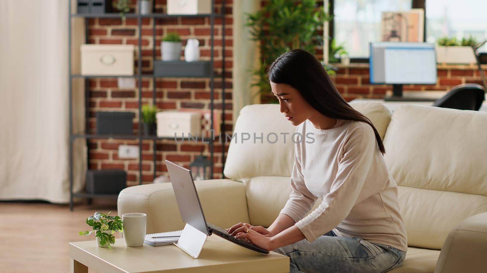 Hurried woman working remotely on laptop while developing startup project because of early deadline. Beautiful freelancer doing remote work on modern computer while developing business ideas at home.