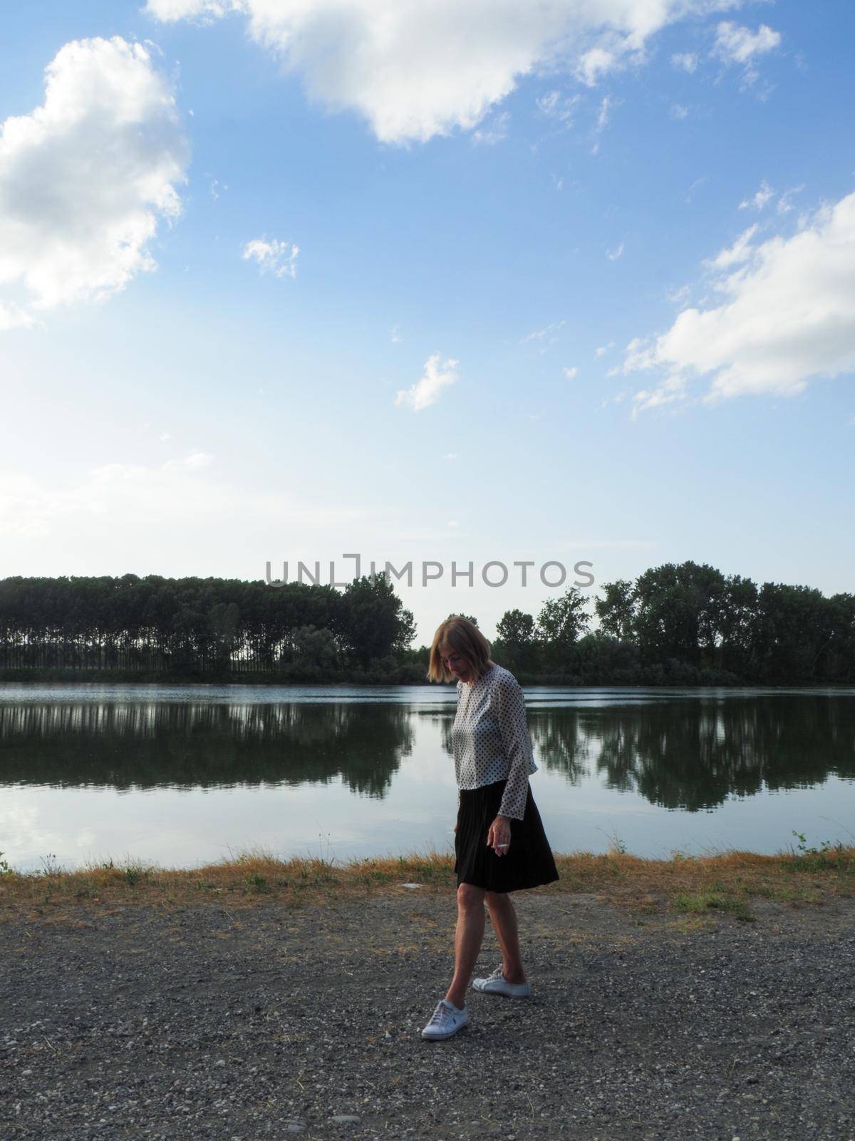 joyful senior woman smoking a cigarette in a park near the water by verbano