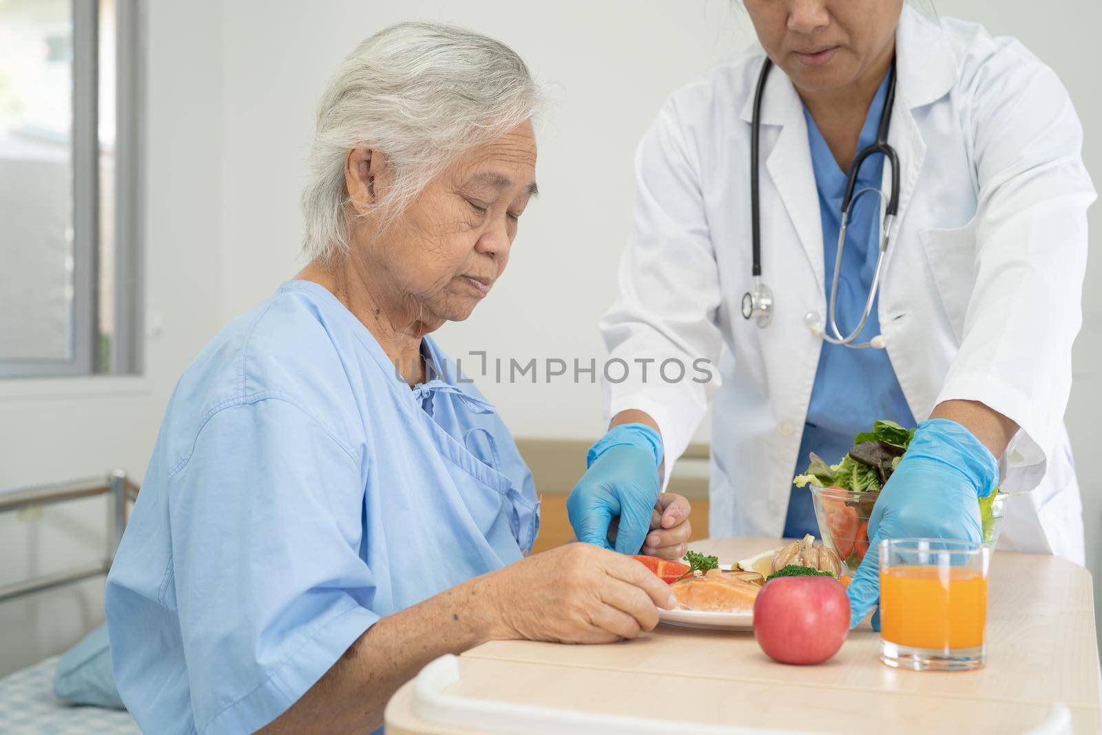 Asian senior or elderly old lady woman patient eating breakfast and vegetable healthy food with hope and happy while sitting and hungry on bed in hospital. by pamai
