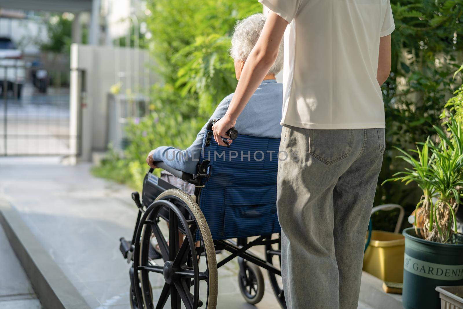 Caregiver help and care Asian senior or elderly old lady woman patient sitting on wheelchair to ramp in nursing hospital, healthy strong medical concept. by pamai