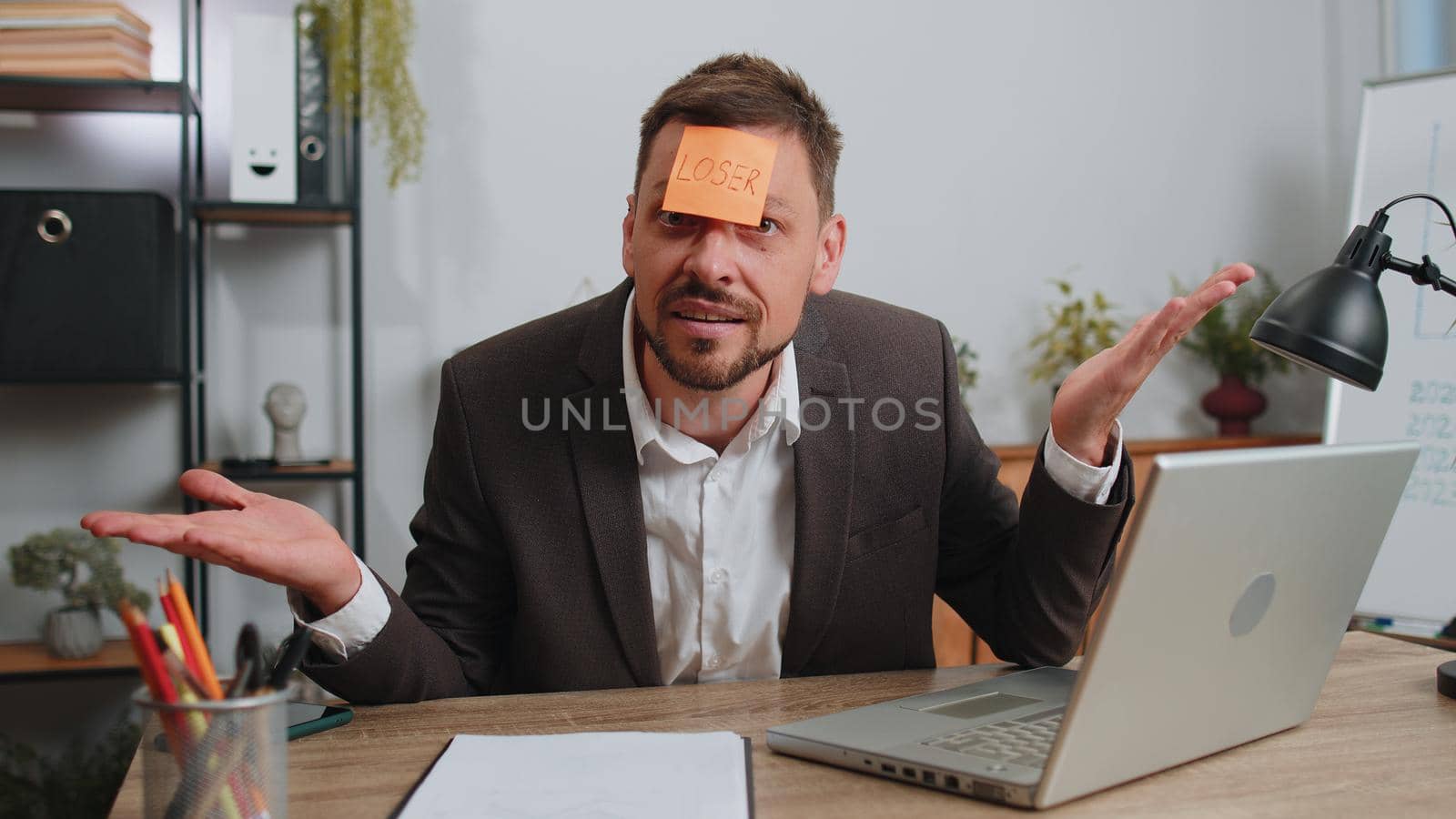 Businessman in suit with inscription note text Loser on forehead working on laptop loses becoming surprised sudden lottery results, bad news, fortune loss, fail at office. Male freelancer business man
