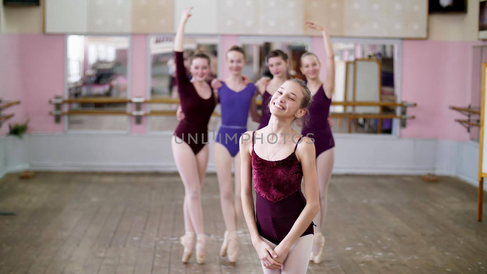 portrait of a young girl ballet dancer in a lilac ballet leotard, smiling, sending an air kiss, gracefully performing a ballet figure. High quality photo