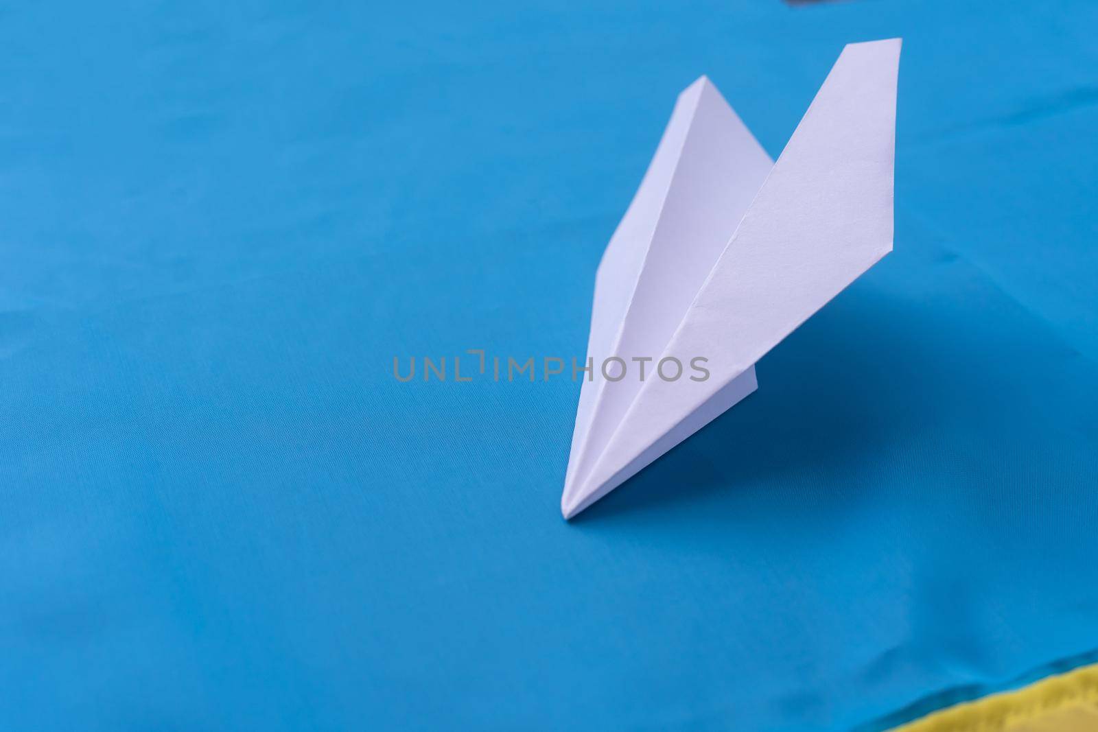White small paper airplane on a blue background.