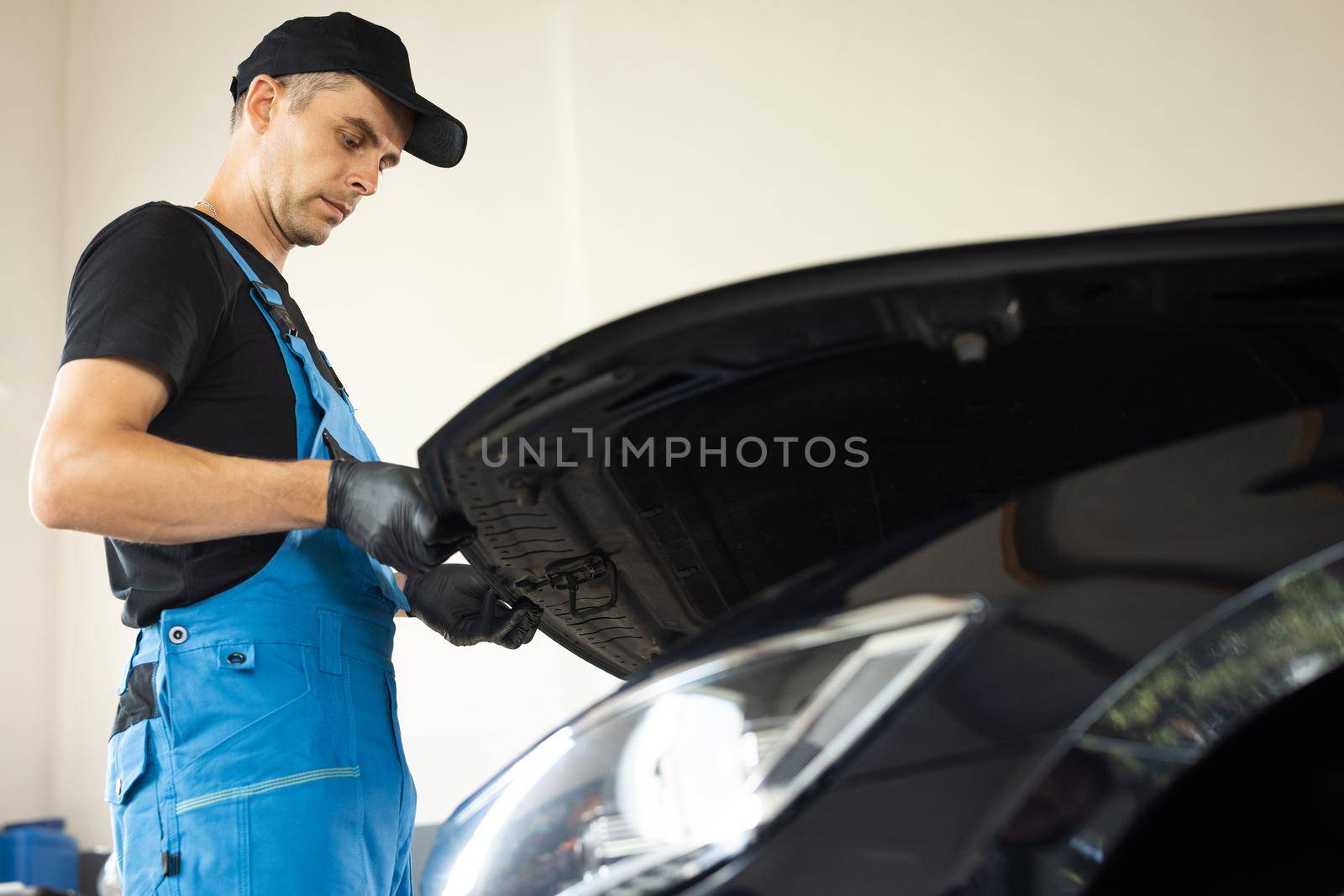 Automotive mechanic man open a car hood and check up the engine. Vehicle service manager worker work in mechanics garage, check and maintenance to repair the motorcar car in workshop.