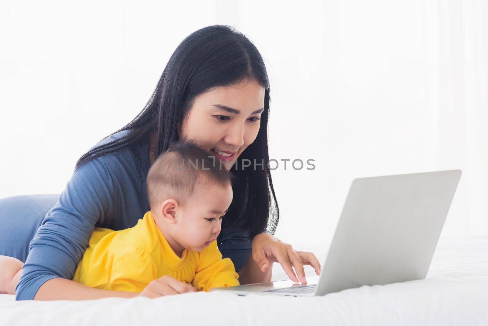 young mother and baby lifestyle working on laptop by Sorapop