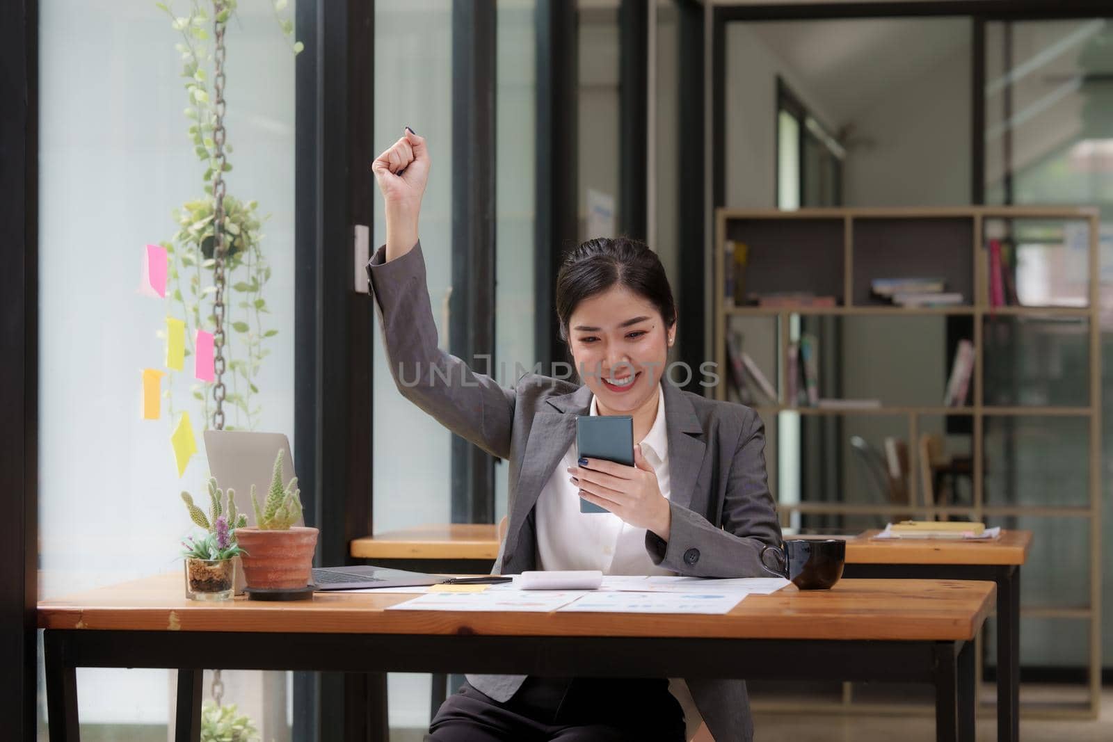 Happy Asian man using smartphone while have a good news working at office.