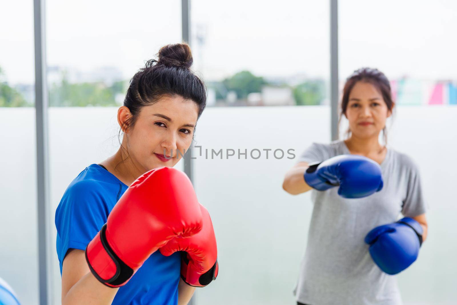 Asian lifestyle adult and young woman smiling sports fitness boxer wearing gloves practicing kick on boxing in sportswear work out indoor yoga studio, sport healthy workout concept