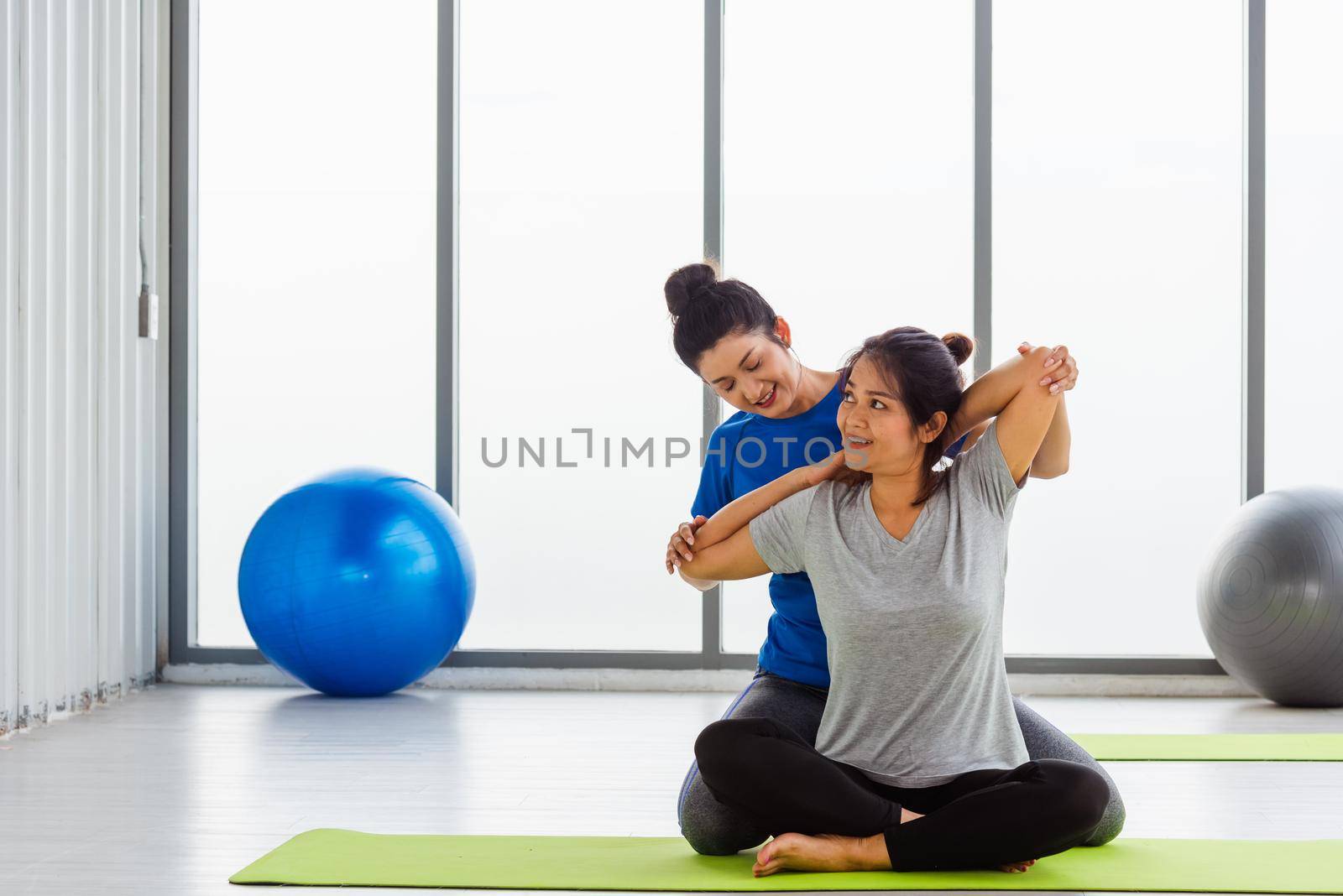 Asian young woman teacher teach adult student doing yoga stretching position in studio. Two woman teaching yoga and fun together, female sport fit workout concept