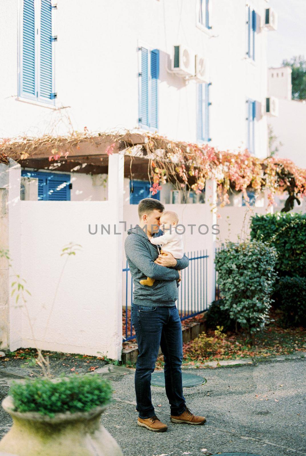 Dad with a baby in his arms stands near the house. High quality photo