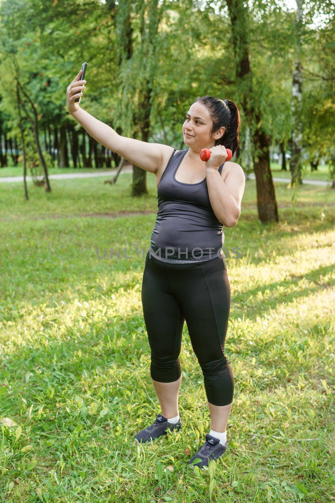 A charming brunette woman plus-size body positive practices sports in nature.