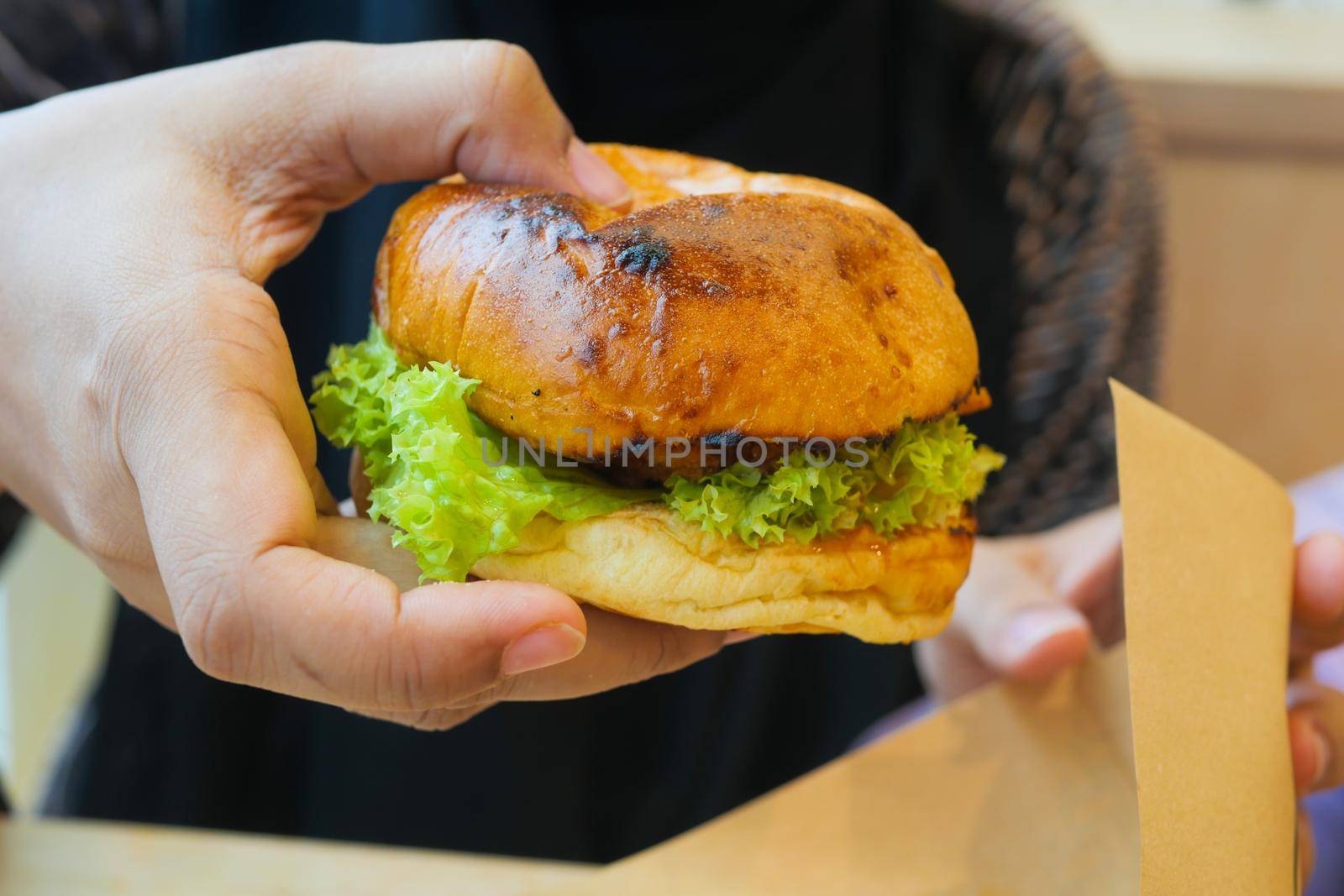 hand holding beef burger on table close up .