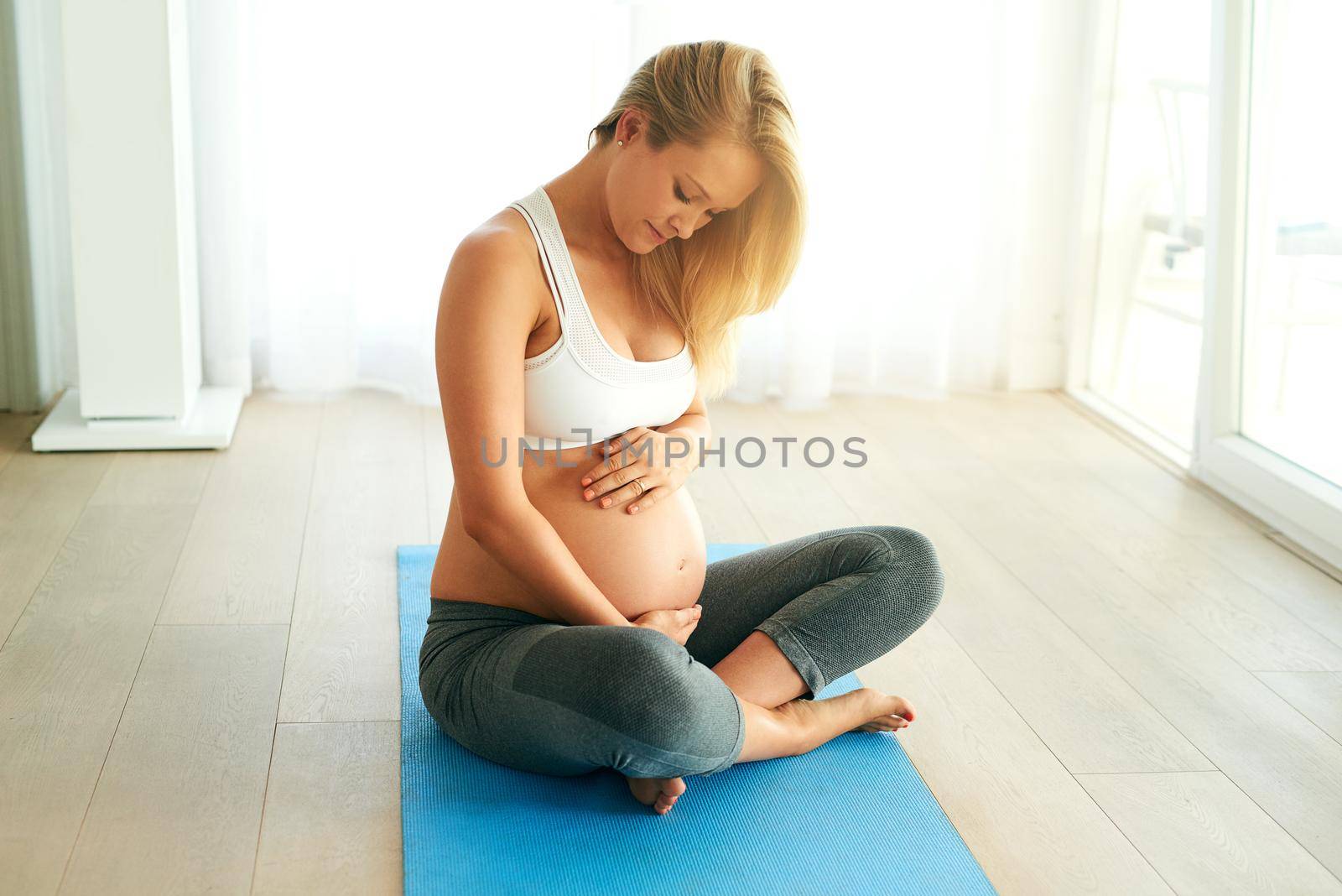 Healthy mama, healthy baby. a pregnant woman working out on an exercise mat at home. by YuriArcurs