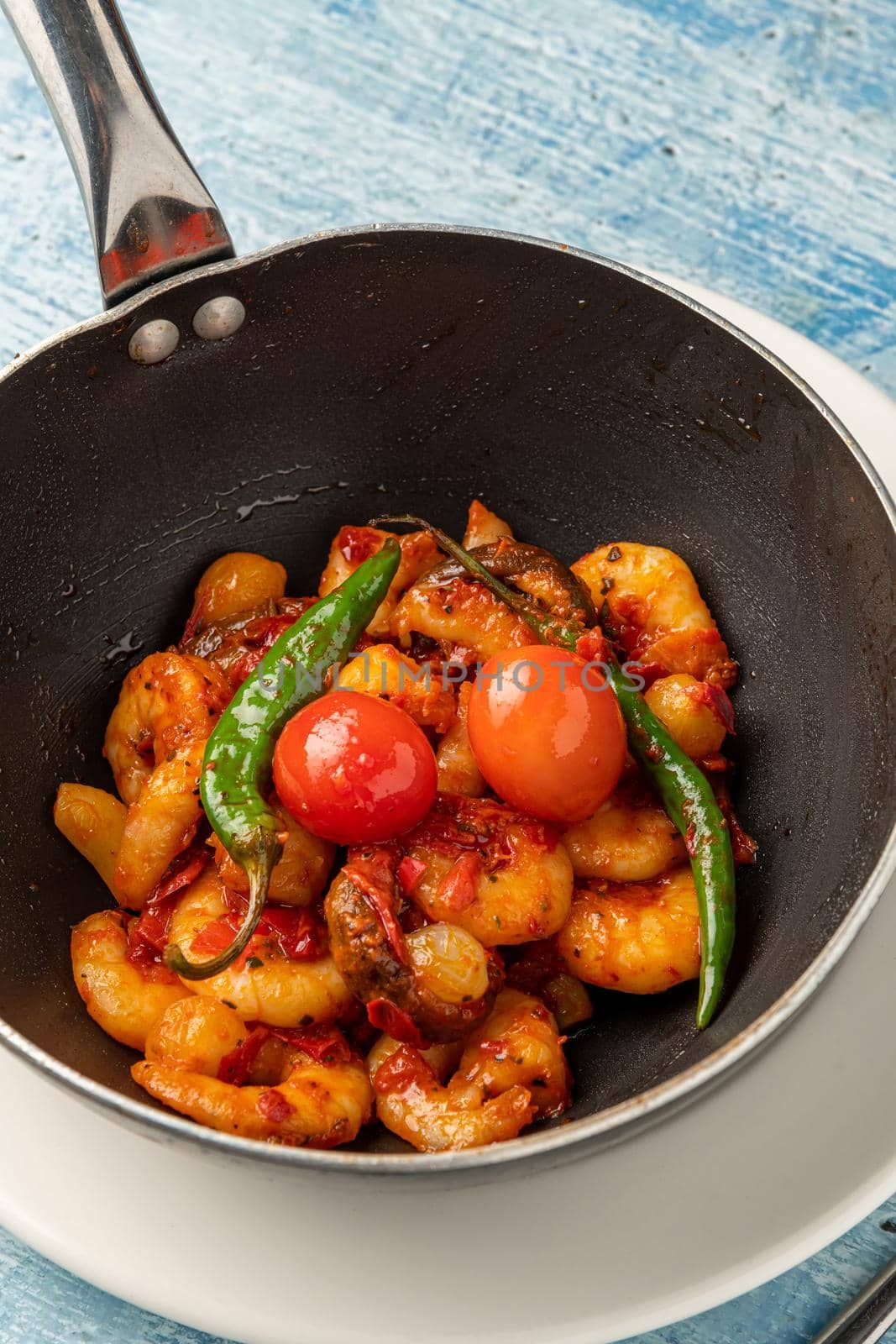 Shrimp casserole with tomatoes, garlic and peppers in black wok pan by Sonat