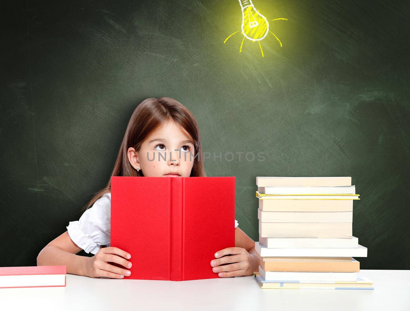 Young cute girl at chalkboard with light bulb over head by Taut