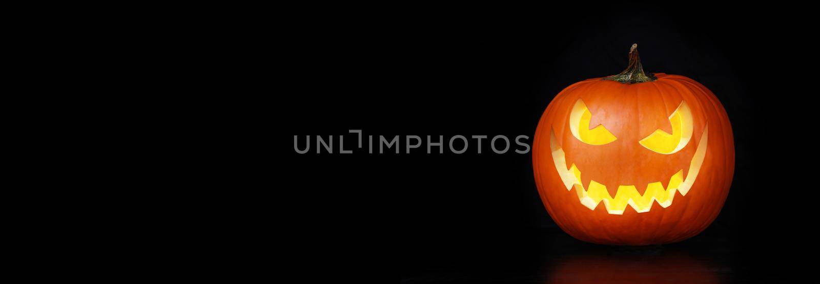Close up view of scary Halloween pumpkin with eyes glowing inside by Taut