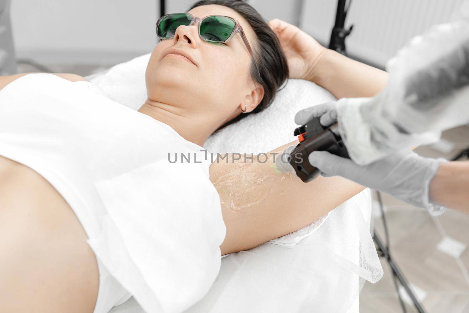 Laser hair removal process. Woman during laser hair removal of armpits and underarms in beauty center. Laser hair removal concept. by gulyaevstudio