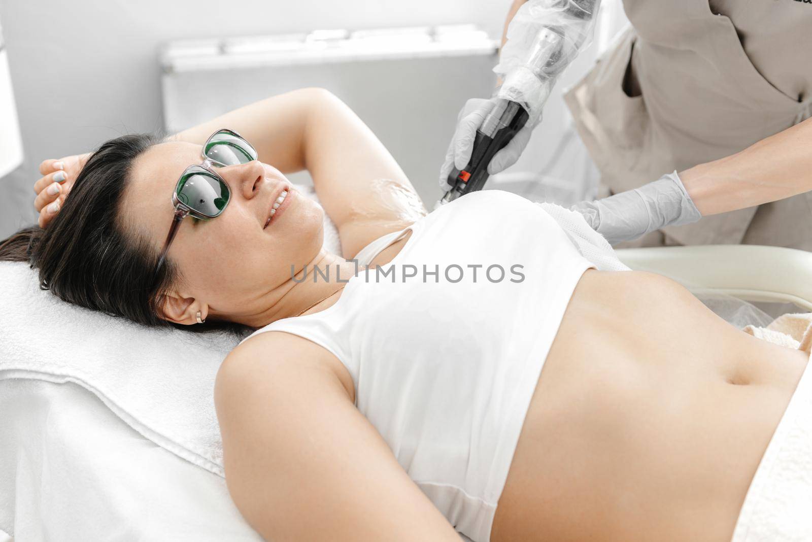 a girl lies on the laser hair removal during the procedure and smiles.