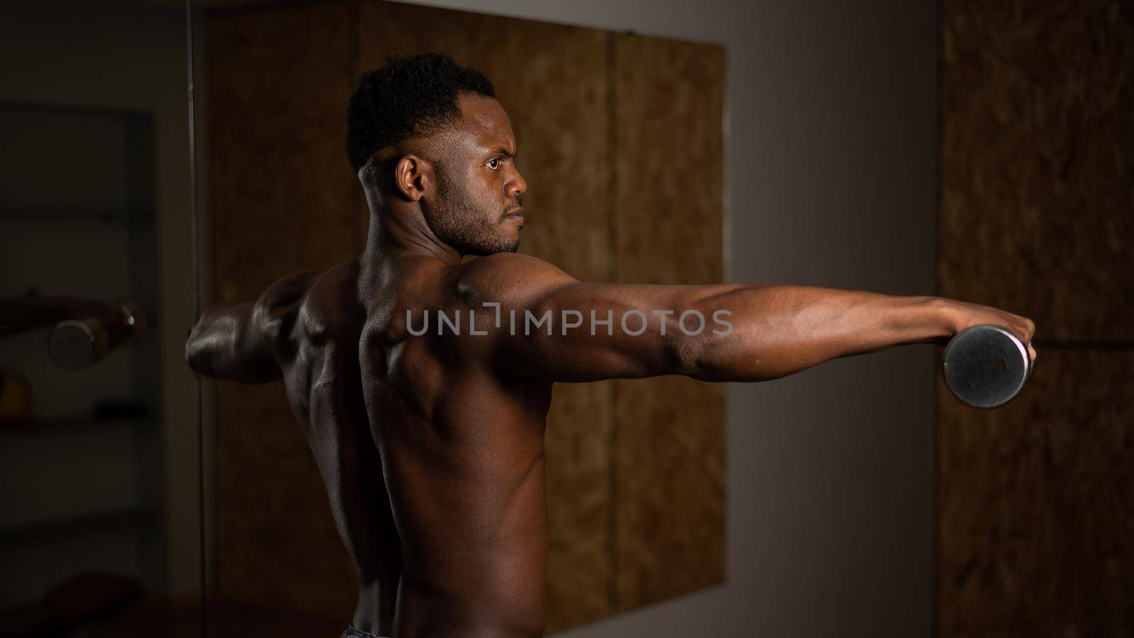 Attractive african american man doing arm exercises with dumbbells