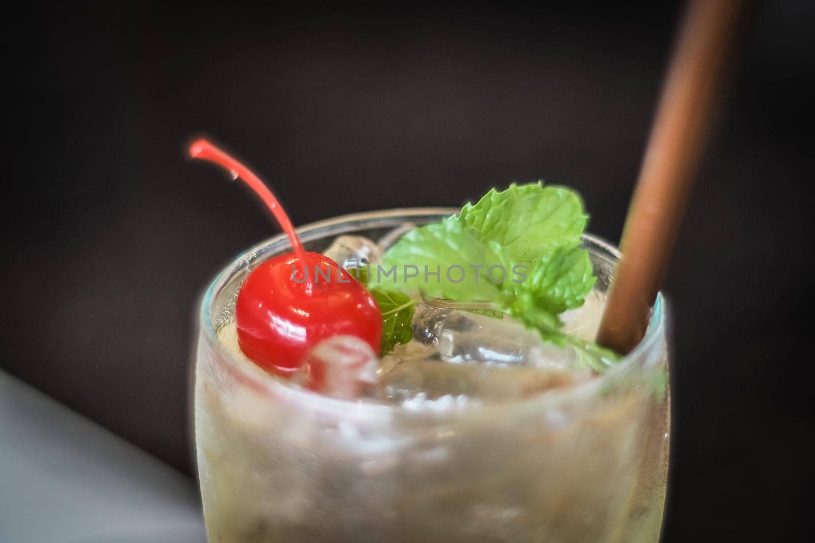 Fresh summer drink mocktail beverage pour in glass cherry and mint leaf decoration on top.
