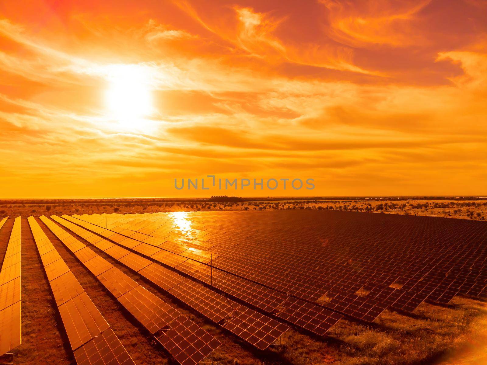 Aerial top view of a solar panels power plant. Photovoltaic solar panels at sunrise and sunset in countryside from above. Modern technology, climate care, earth saving, renewable energy concept