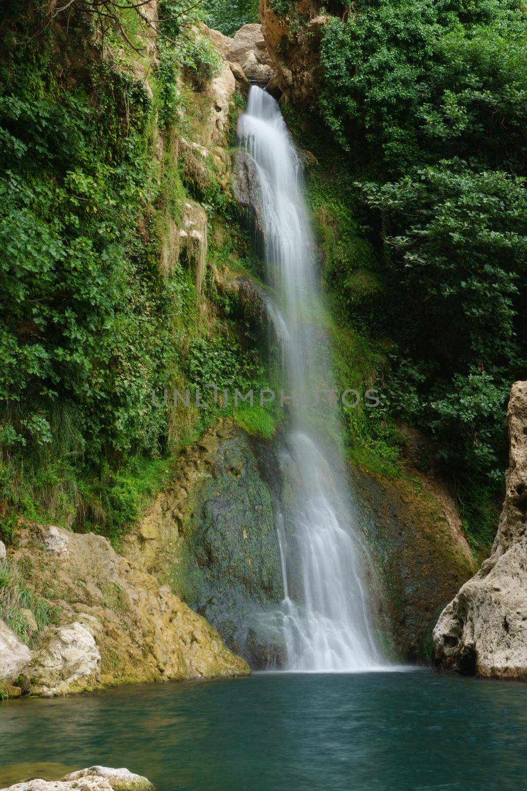 large waterfall over a natural pool for bathing with cold and crystalline water, silk effect, long exposure.