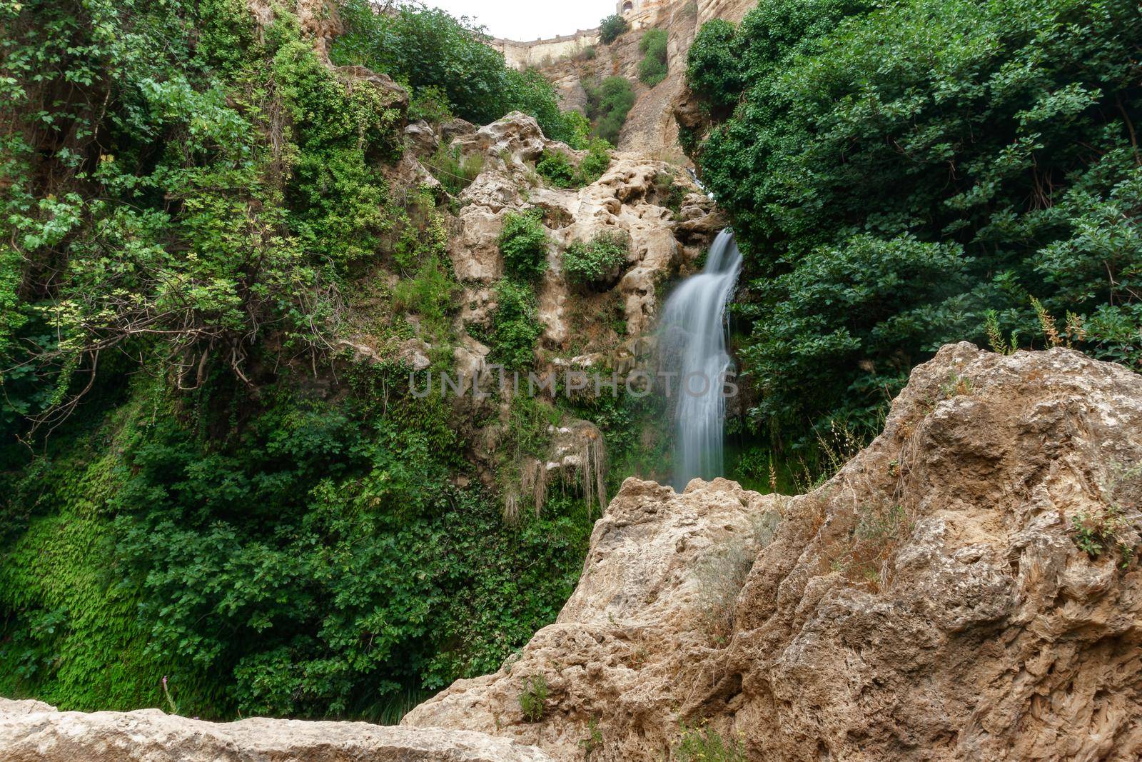 large waterfall over a natural pool for bathing with cold and crystalline water, silk effect, long exposure.