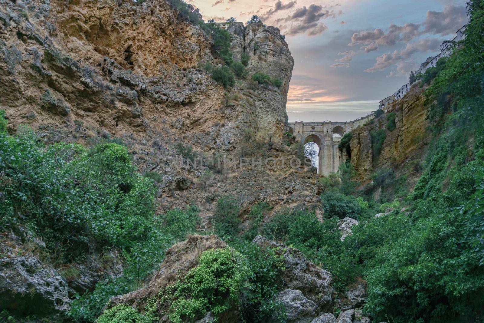 view from the river of the new bridge of ronda ,malaga,spain, with dramatic colorful sky at sunset