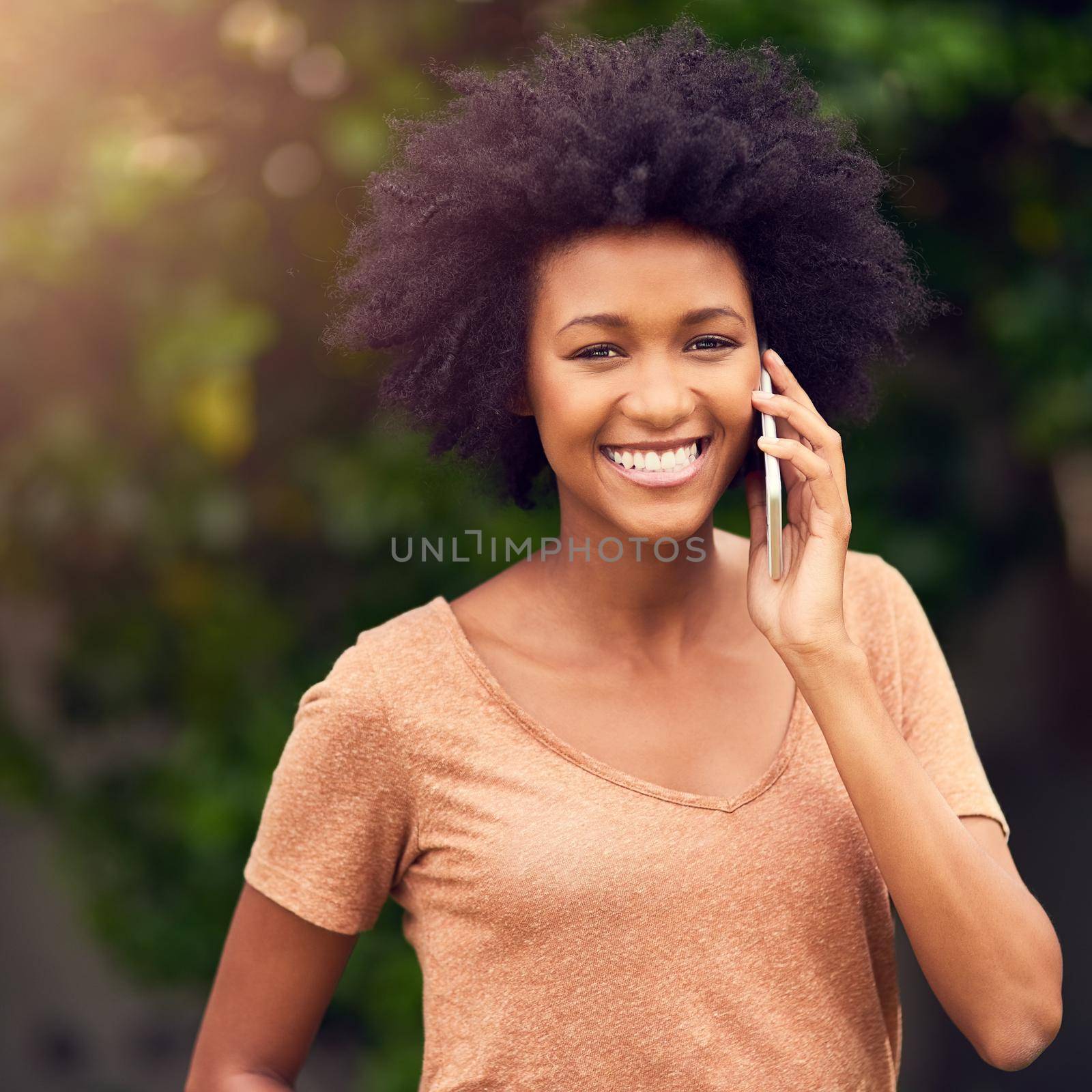 I feel happy and connected in the great outdoors. a young woman talking on her cellphone while spending the day outdoors