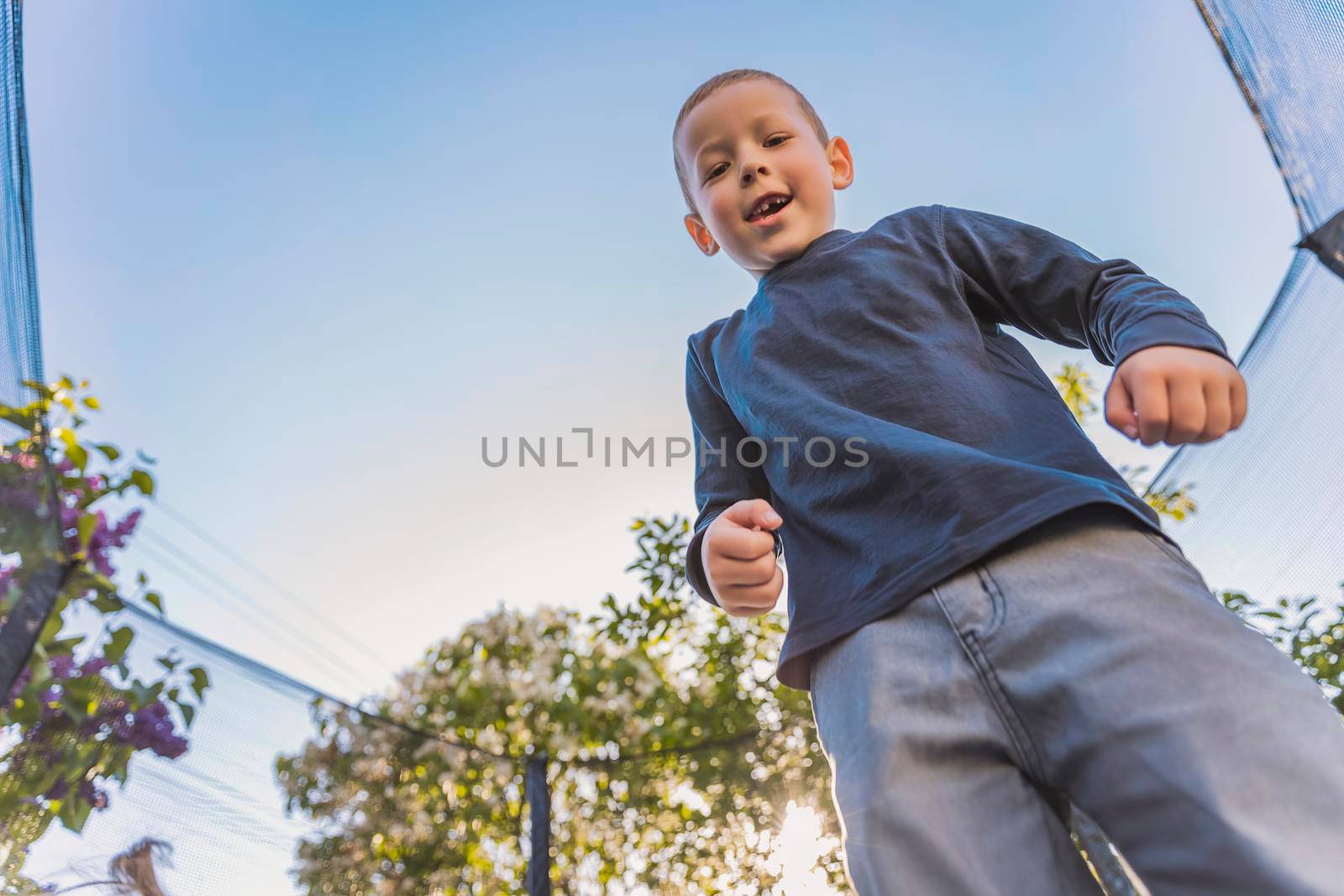 little boy jumps on a trampoline that stands in the yard
